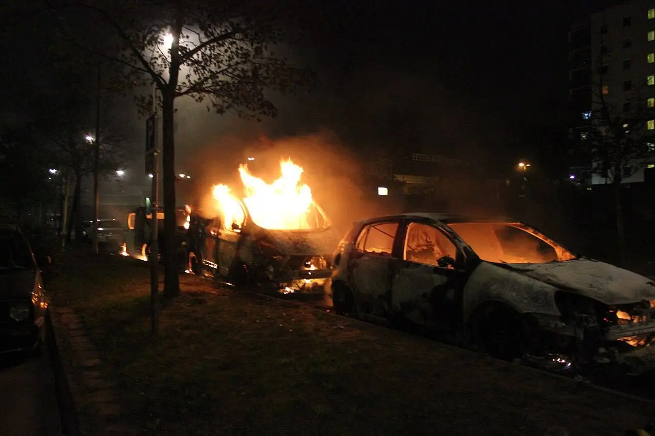 Felgyújtott autók Stockholm Husby városrészében a 2013-as zavargások második napján. Fotó: Telefonkiosk / Wikimedia Commons